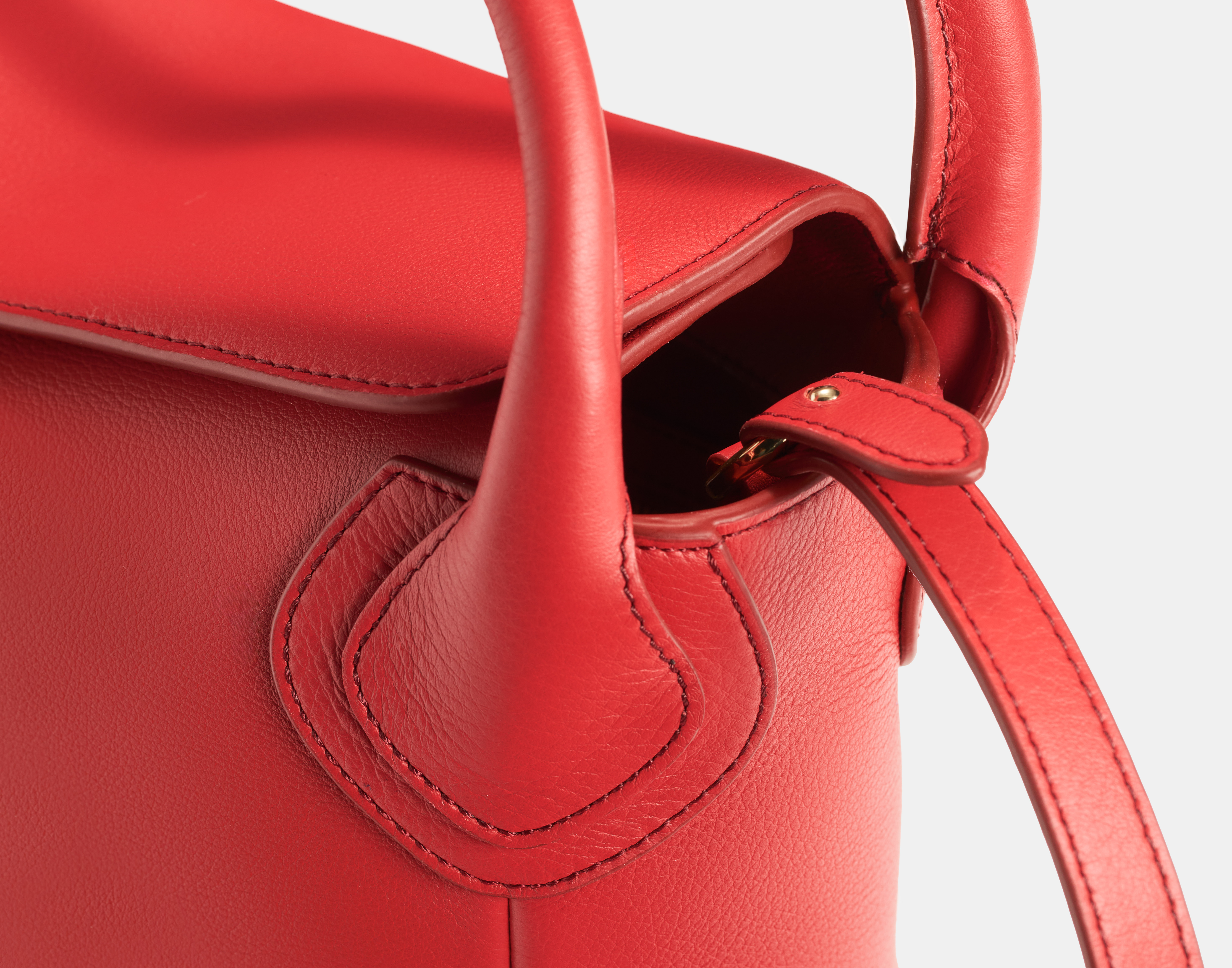 Close-up of the red 'The Maria' handbag handle and stitching detail
