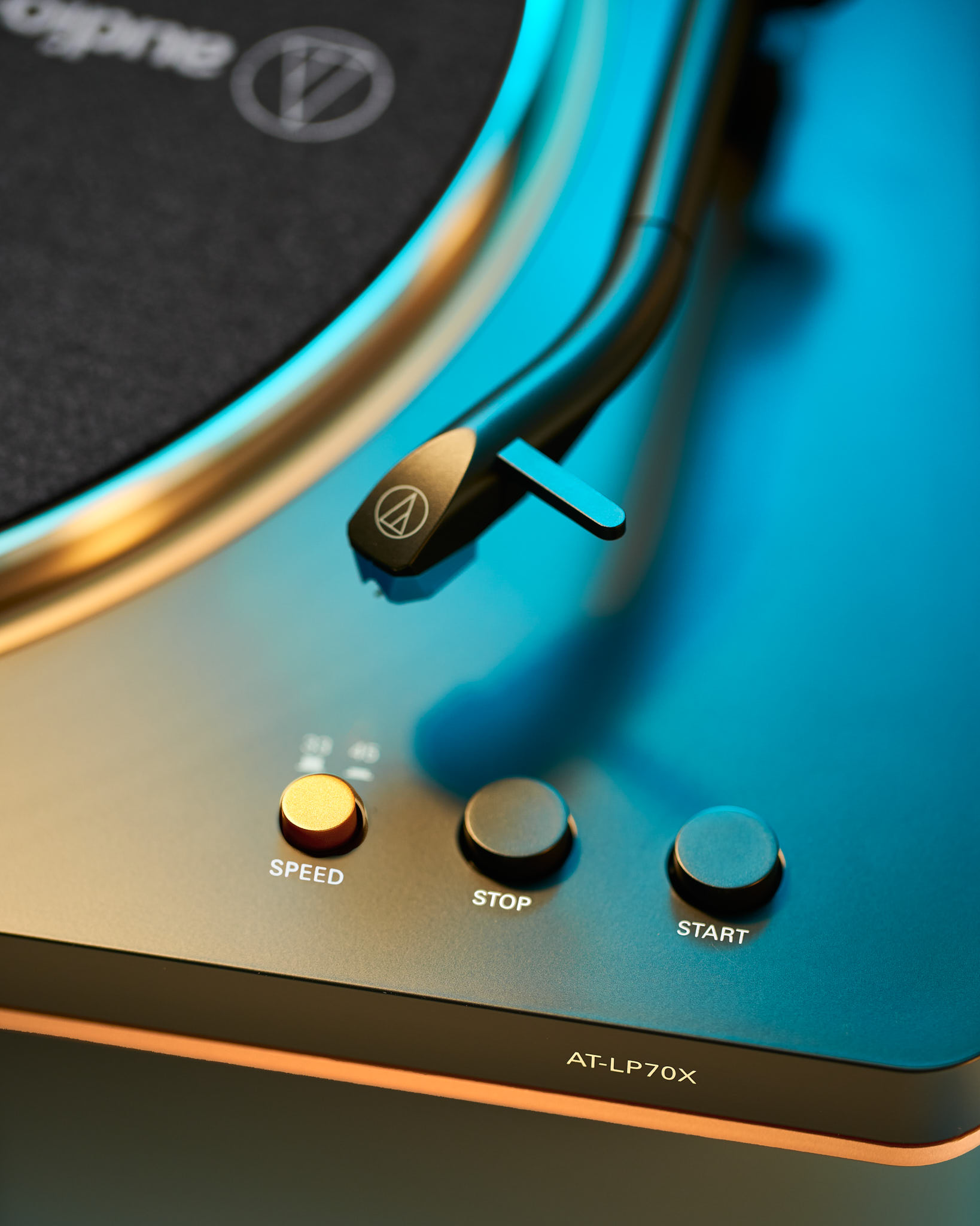 Close-up campaign shot of an Audio-Technica AT-LP70X turntable with dramatic gold and teal lighting
